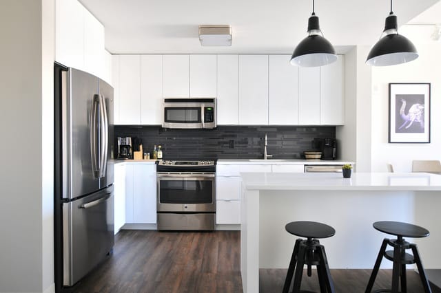 Cuisine blanche équipée avec îlot central et tabourets noirs