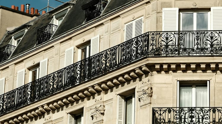 Façade haussmannienne aux balcons en fer forgé sous un ciel bleu