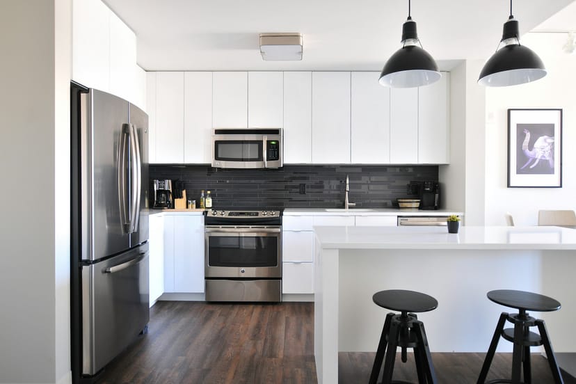 Cuisine blanche équipée avec îlot central et tabourets noirs