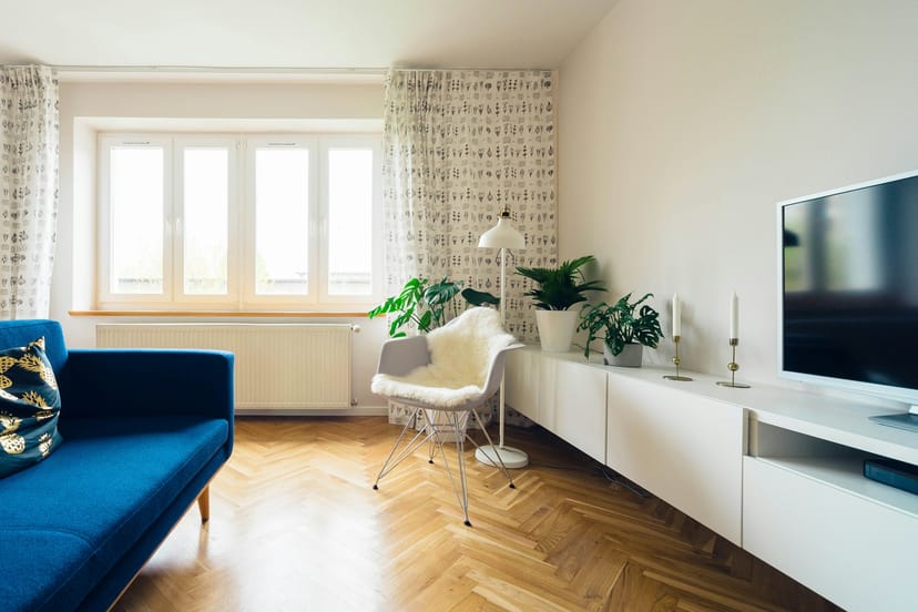Séjour lumineux au parquet en chevrons, canapé bleu nuit et grandes fenêtres